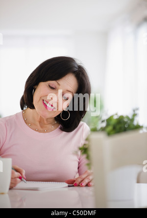 Mixed Race woman écrit dans le journal Banque D'Images