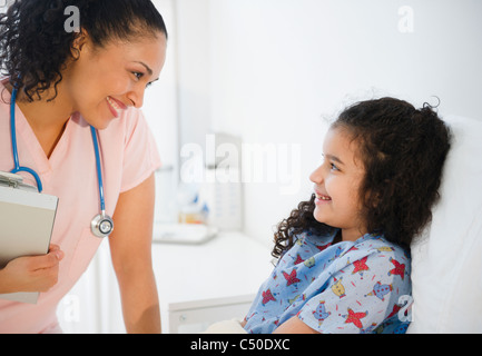 Smiling nurse talking to girl in hospital bed Banque D'Images