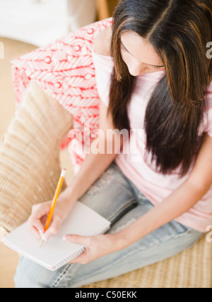 Hispanic woman writing in notebook Banque D'Images