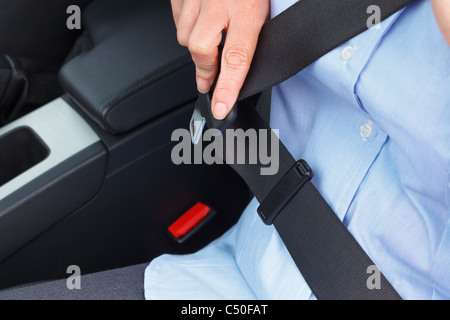 Photo d'une business woman sitting in a car mettre sur sa ceinture de siège Banque D'Images