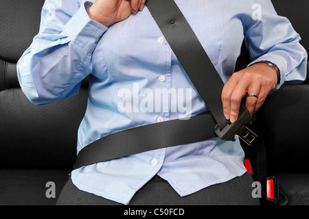 Photo d'une business woman sitting in a car mettre sur sa ceinture de siège Banque D'Images