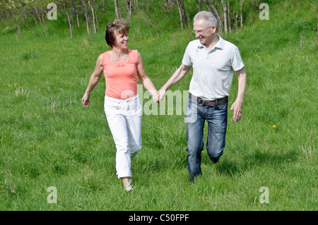 Middle-aged couple marche main dans la main dans un pré Banque D'Images