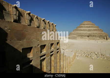 Une ligne de statues cobra sur un tombeau et la Pyramide à Degrés de Zoser (Djoser) font partie de la grande nécropole de Saqqara, Egypte Banque D'Images