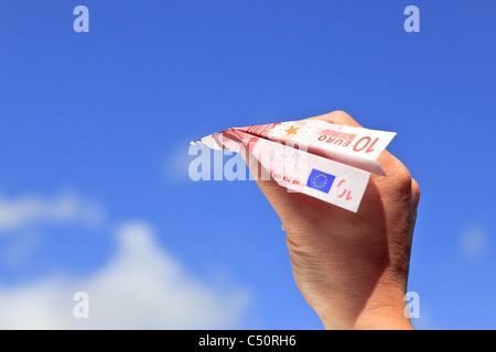 Photo d'une main de femme sur le lancement d'un dix du papier des billets avion dans le ciel par une journée ensoleillée. Banque D'Images