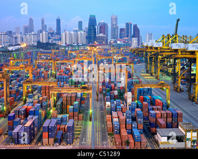 Une soirée vue d'un terminal à conteneurs de Singapour jusqu'après le crépuscule, avec le contraste de la ville en arrière-plan Banque D'Images