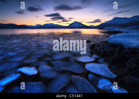 La dérive des flocons de glace contre le coucher du soleil dans le détroit Tjeldsundet, Troms County, en Norvège. Banque D'Images