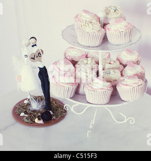 Petits gâteaux de mariage on cake stand à côté de Bride and Groom cake topper Banque D'Images