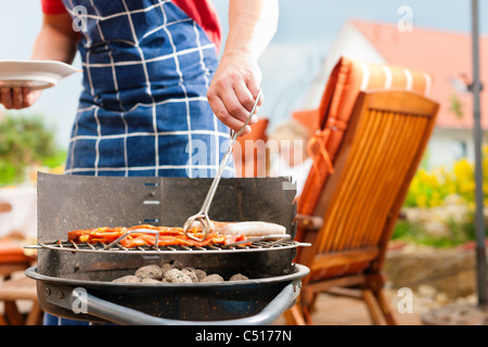 Happy Family having a barbecue en été ; le père se trouve à côté de l'incendie Banque D'Images