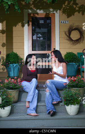 Et ethniques caucasian woman sitting on Front Porch de chambre à parler et rire. Banque D'Images