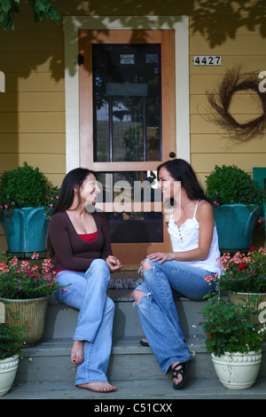 Et ethniques caucasian woman sitting on Front Porch de chambre à parler et rire. Banque D'Images