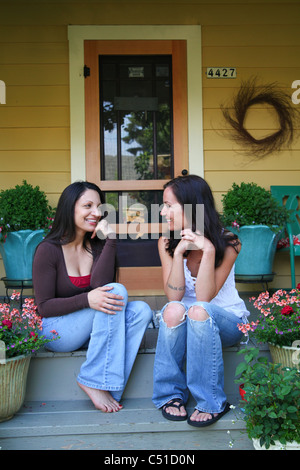 Et ethniques Caucasian woman sitting on Front Porch de chambre à parler et rire. Banque D'Images