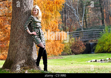 Femme blonde appuyée contre un arbre dans un parc, New Jersey Banque D'Images