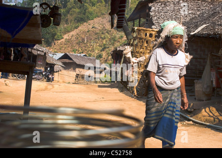 Une femme de la tribu ethnique est porteur d'un panier pour recueillir les feuilles sèches dans un camp de réfugiés dans le Nord de la Thaïlande. Banque D'Images