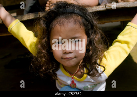 Une jeune fille de réfugiés Karen Paduang avec les cheveux bouclés est relaxant à son domicile dans un camp de réfugiés birmans en Thaïlande du Nord. Banque D'Images