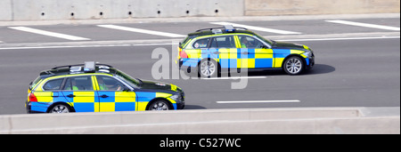 Deux voitures de police police Essex des déplacements à grande vitesse sur autoroute M25 pilote officier wearing high vis jacket England UK Banque D'Images