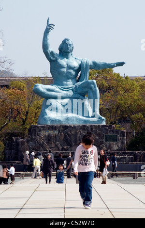 Jeune fille qui marche en face de la Statue de la paix de Nagasaki, Parc de la paix, Urakami, Nagasaki, Japon. Banque D'Images