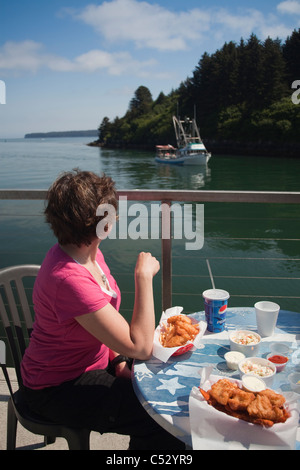 Femme regardant et manger un déjeuner de fruits de mer à côté du canal Chowder House à Kodiak, l'île Kodiak, Alaska Banque D'Images