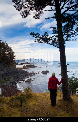 Female hiker profiter de la vue donnant sur la baie de Chiniak à Fort Abercrombie State Historical Park sur l'île Kodiak, Alaska Banque D'Images