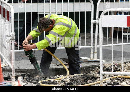 Un ouvrier à l'aide d'un marteau pneumatique des travaux routiers à Londres, Angleterre Banque D'Images