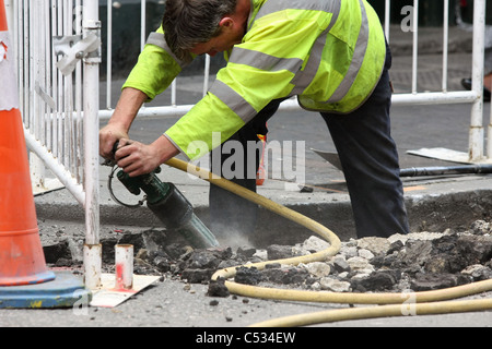 Un ouvrier à l'aide d'un marteau pneumatique des travaux routiers à Londres, Angleterre Banque D'Images