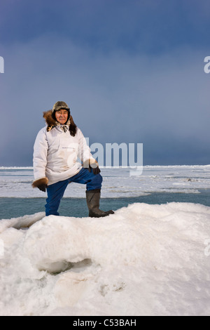 En Esquimau Inupiak mâle parc traditionnel stans sur une des crêtes de pression, la glace de mer de Tchoukotka près de Barrow, Alaska Banque D'Images
