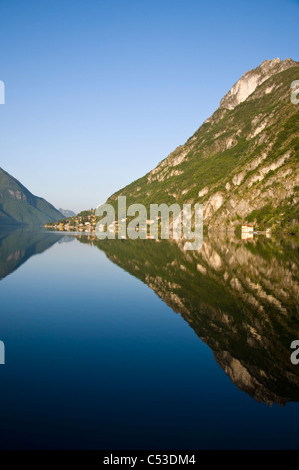 Village de Cima reflète dans les eaux calmes du lac de Lugano tiré de Porlezza Banque D'Images