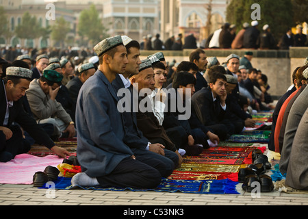 Les fidèles musulmans s'agenouiller sur des tapis de prière à l'extérieur de la mosquée Id Kah à la fin du ramadan. kashgar, la province du Xinjiang, Chine Banque D'Images