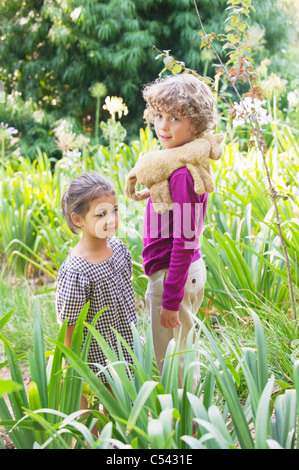 Portrait of a smiling boy standing avec petite fille dans un jardin