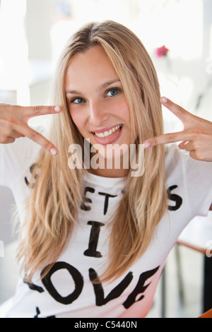 Portrait d'une belle femme montrant signe de paix dans un café Banque D'Images