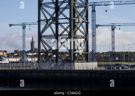 Les grues de construction à Glasgow sur le site Scottish Hydro Arena, Glasgow, Ecosse, Royaume-Uni. Tour de l'université à l'horizon. Banque D'Images