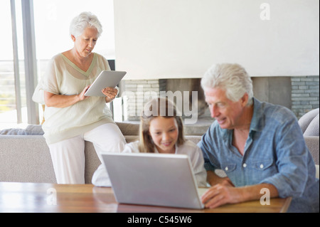 L'homme à l'aide d'un ordinateur portable avec sa petite-fille et sa femme travaille sur un digital tablet in background Banque D'Images