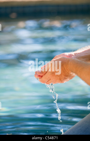 Close-up de la main d'un homme toucher l'eau de la piscine Banque D'Images