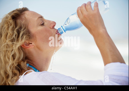 Profil de côté d'une belle femme à boire de l'eau purifiée Banque D'Images