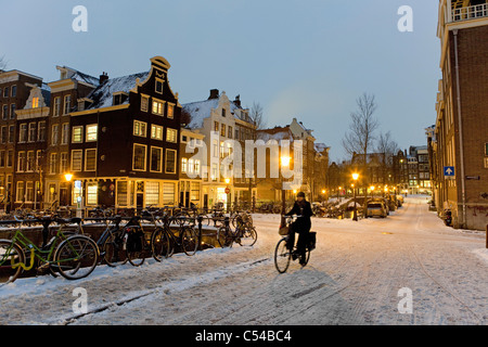 Les Pays-Bas, Amsterdam, l'hiver, la neige. Cycliste sur pont-canal au crépuscule. Banque D'Images