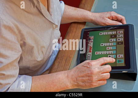 Femme jouant un jeu de patience jeu de carte sur un Apple iPad tablet computer Banque D'Images