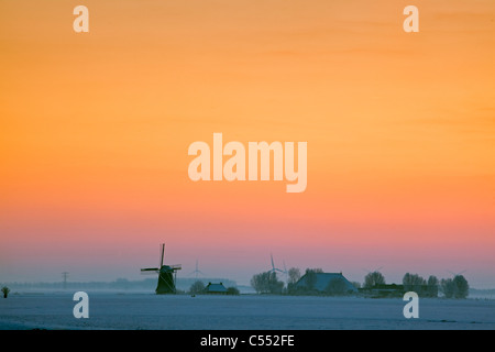 Les Pays-Bas, l'Tritzum, Moulin et ferme dans la neige au coucher du soleil. Banque D'Images