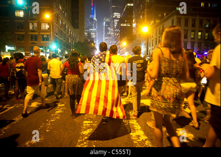 Un spectateur portant un drapeau américain quitte après affichage de la 35e assemblée annuelle de Macy's Fourth of July fireworks à New York Banque D'Images