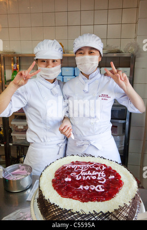 Femme debout chefs dans une cuisine près de un gâteau, Beijing, Chine Banque D'Images