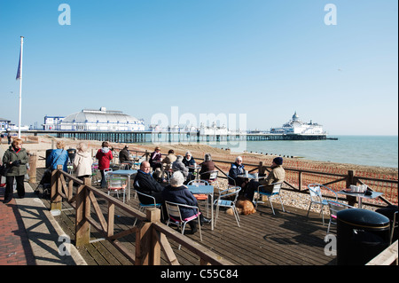 Café en plein air au front de mer d'Eastbourne en Angleterre avec la jetée victorienne dans l'arrière-plan Banque D'Images