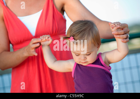 Femme d'aider sa fille à marcher Banque D'Images