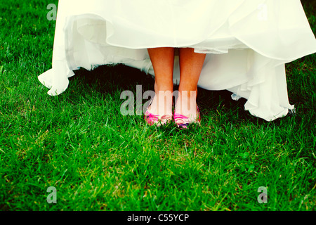 Pieds de mariée en robe de mariage sur l'herbe Banque D'Images