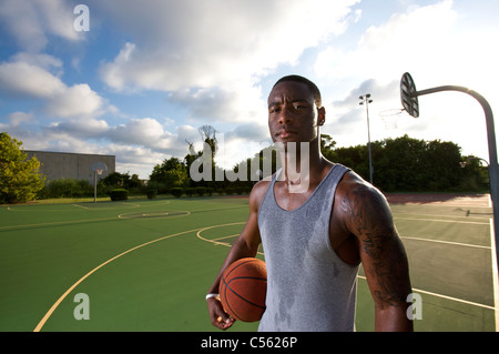 Homme debout devant une cour de basket-ball après avoir joué, en sueur Banque D'Images