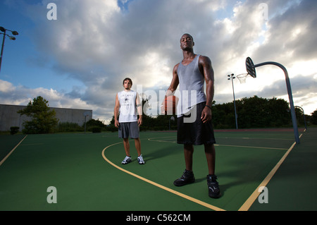 Les mâles après après avoir joué au basket-ball sur une cour, ciel dramatique Banque D'Images