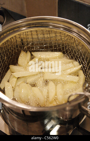 Plaquettes fait maison pommes de terre King Edward dans la cuisine de l'huile végétale chaude bouillonnant dans une puce pan dans la cuisine britannique Banque D'Images