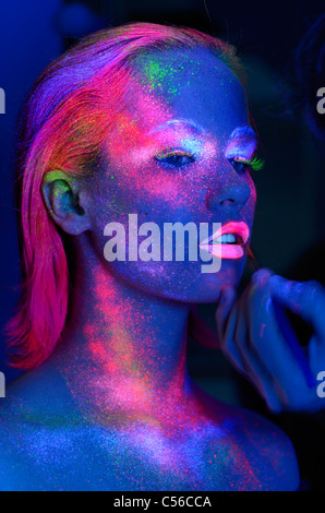 Modèle féminin de rouge à lèvres et le maquillage fluorescent appliqué sous les lumières noires bleu profond Banque D'Images