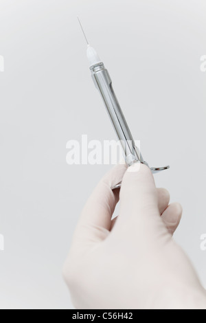 Close-up of human hand holding needle against white background Banque D'Images