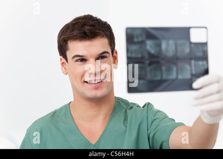 Young smiling doctor l'analyse d'un détail de radiographie dentaire Banque D'Images