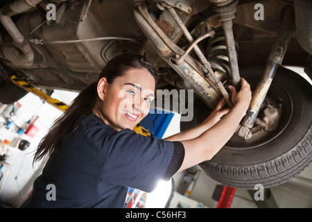 Portrait of smiling young mechanic inspectant un CV sur un compte rendu de la voiture en atelier de réparation automobile Banque D'Images