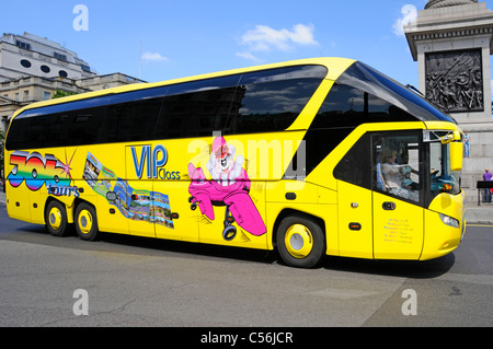 Motifs graphiques sur le côté du bus touristique allemand jaune Autocar passant devant la colonne de Nelsons ciel bleu jour d'été à Trafalgar Square Londres Angleterre Royaume-Uni Banque D'Images