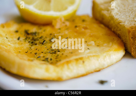 Saganaki - un plat grec de kefalograviera, kasseri, kefalotyri, ou le fromage feta, pan et poêlé servi avec du citron et du pain Banque D'Images